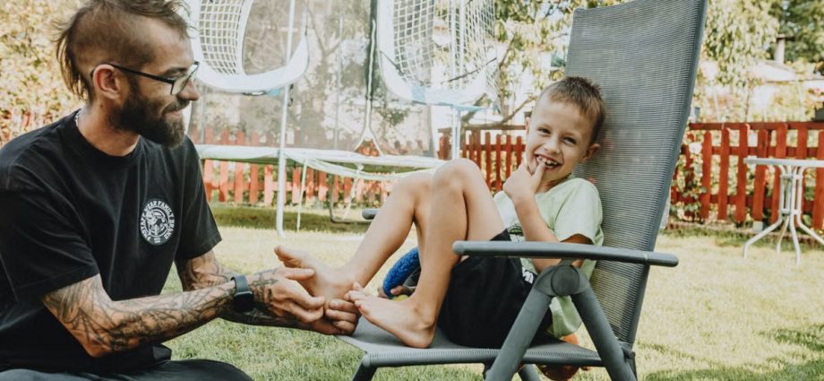 Playful interaction between a father and son in a sunny backyard setting.