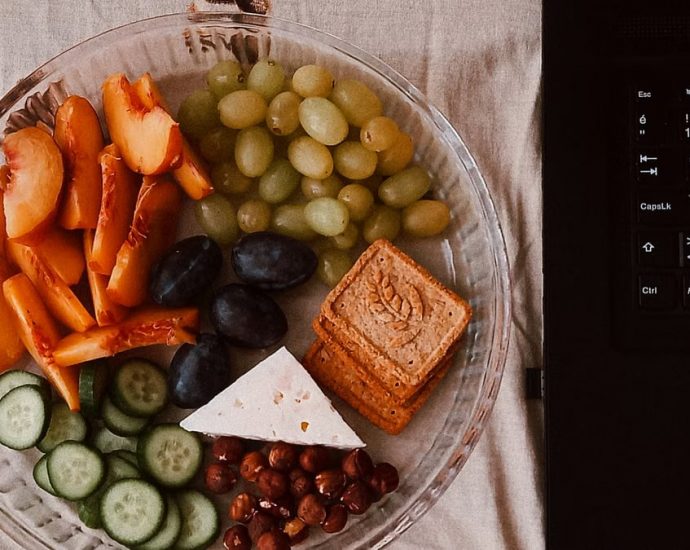 A delightful snack plate with fruits, cheese, and a laptop for a healthy lifestyle.