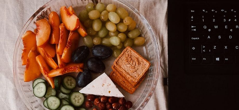 A delightful snack plate with fruits, cheese, and a laptop for a healthy lifestyle.